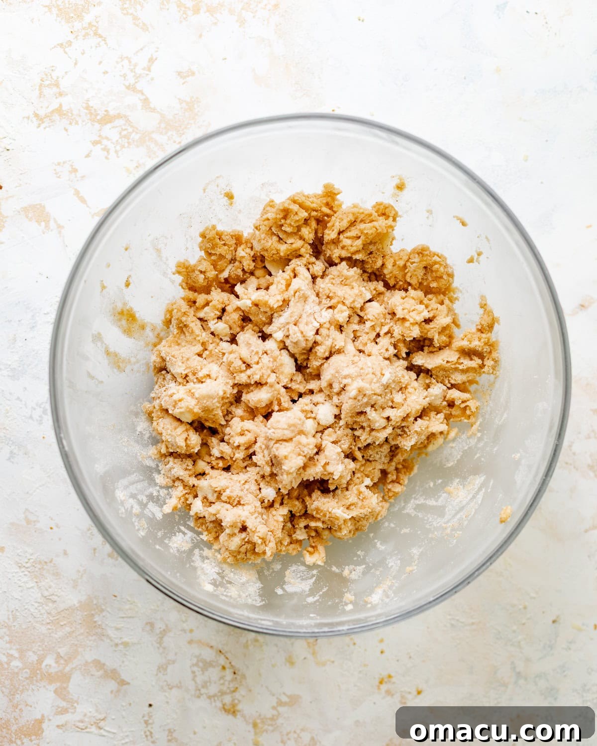 A bowl shows the crumbly, shaggy texture of the mixed cobbler topping, ready for chilling.