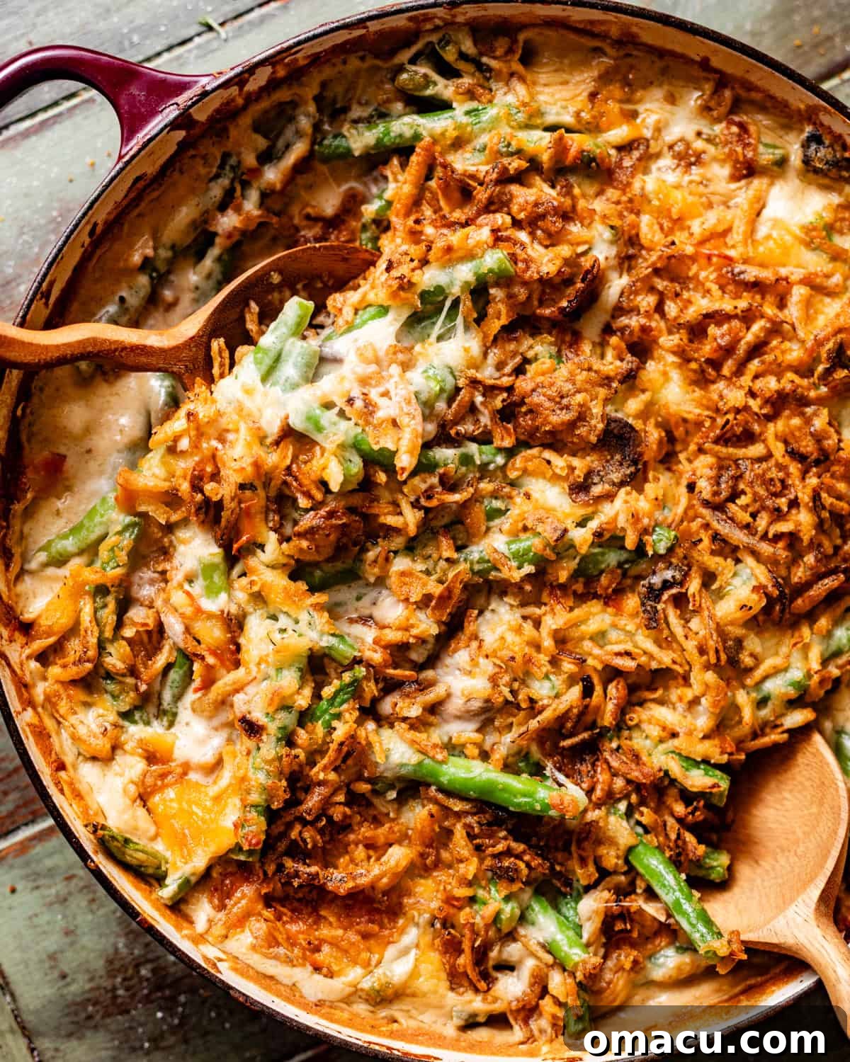 A vibrant photo of green bean casserole in a rustic baking dish with serving spoons, showcasing its golden-brown topping and creamy interior.