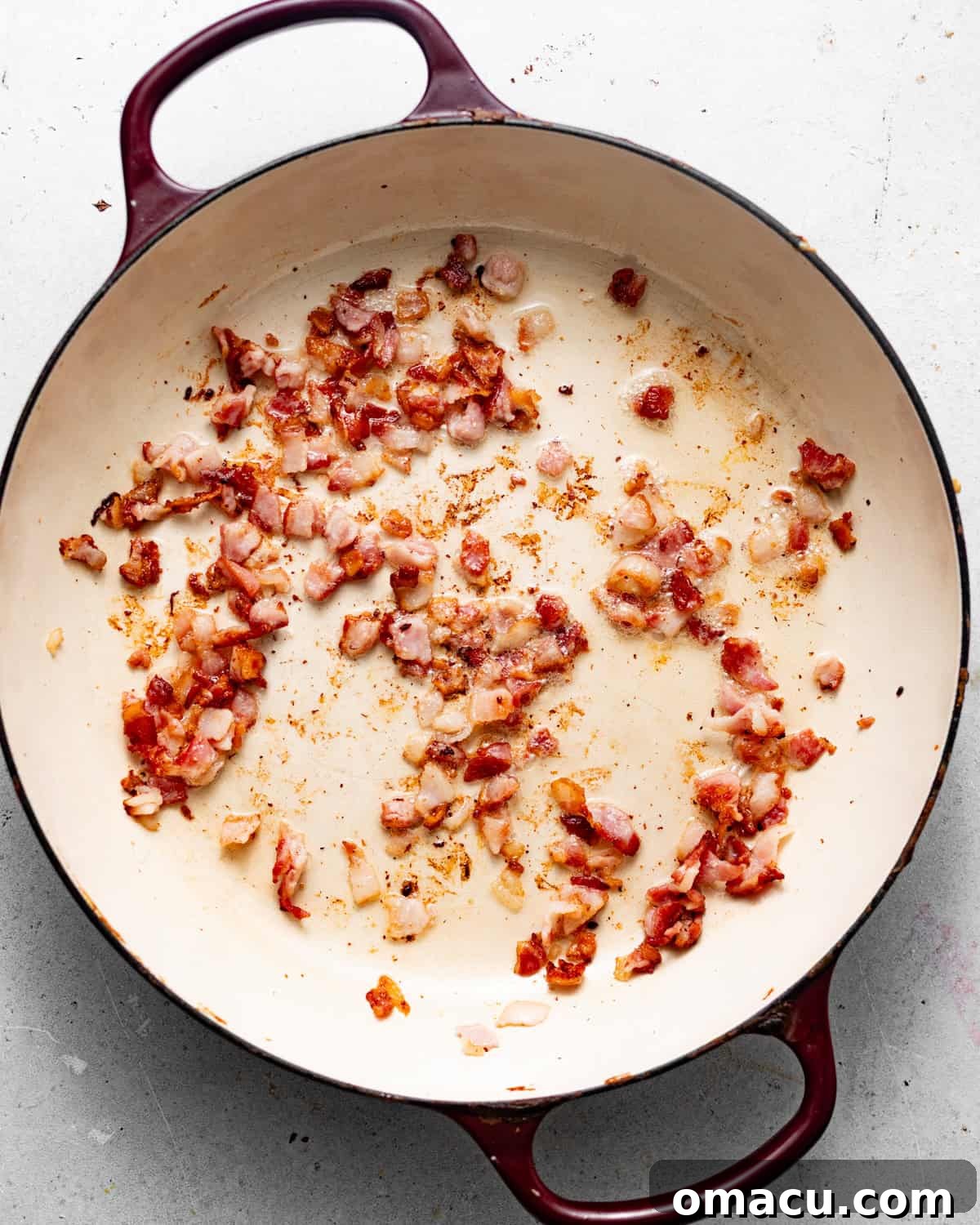 Chopped bacon sizzling and cooking in a large skillet, rendering its fat to create a flavorful base.