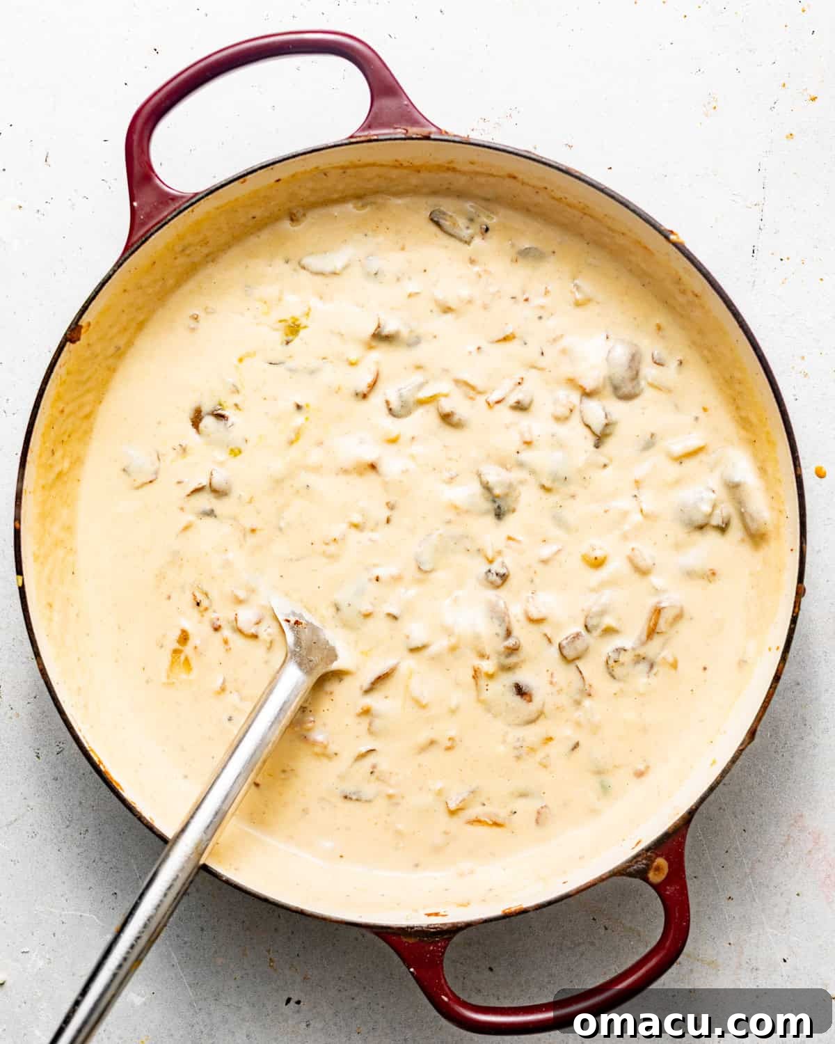 A close-up of the homemade creamy sauce for the green bean casserole, rich and smooth, simmering in a skillet.