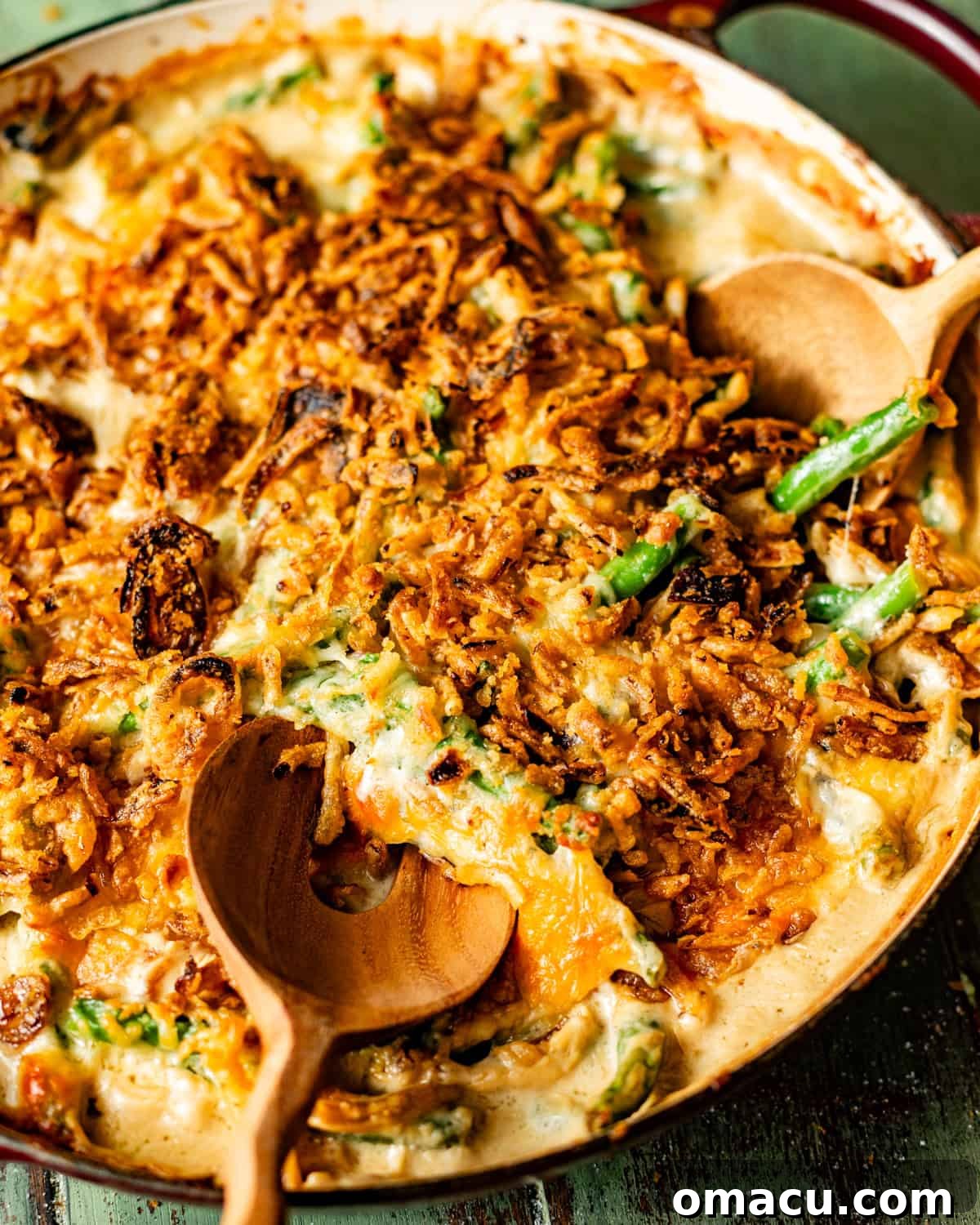 A close-up shot of the perfectly baked green bean casserole in a rustic skillet, with serving spoons invitingly placed, highlighting its creamy texture and crispy topping.