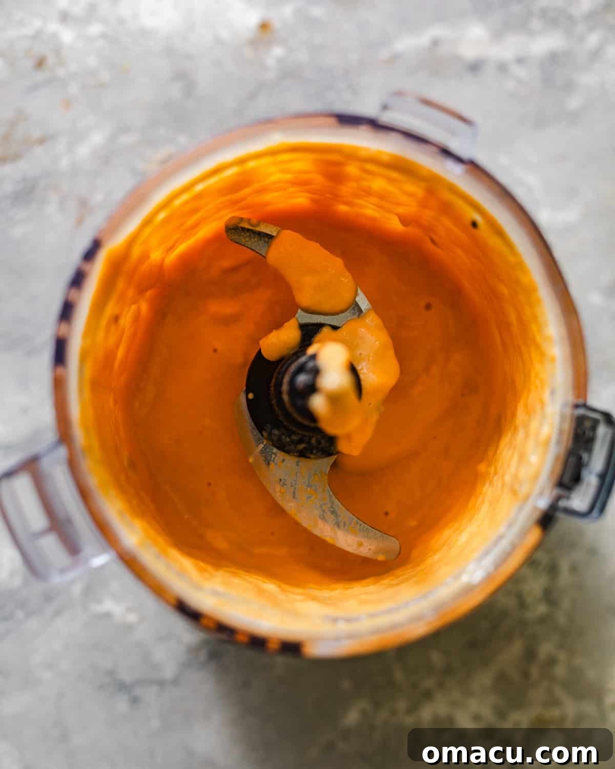 Sweet potato puree being blended in a food processor with buttermilk, sour cream, and vanilla extract for biscuit dough.