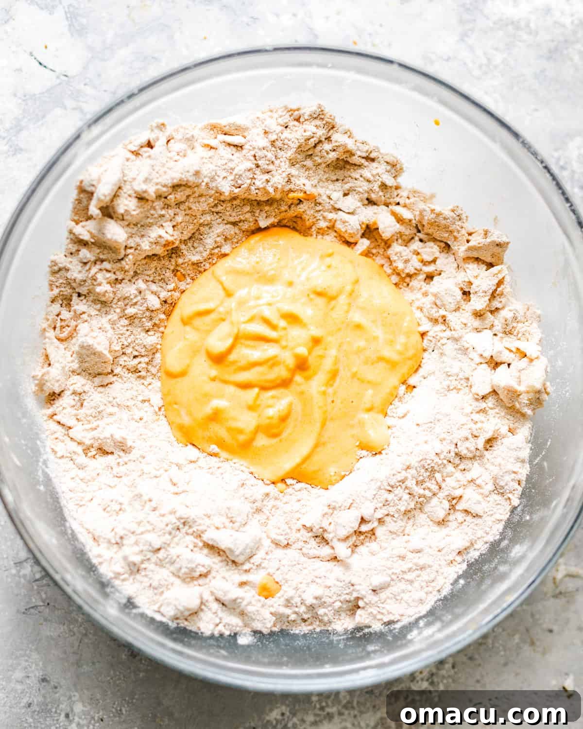 The blended sweet potato mixture being poured into a bowl of dry biscuit ingredients.