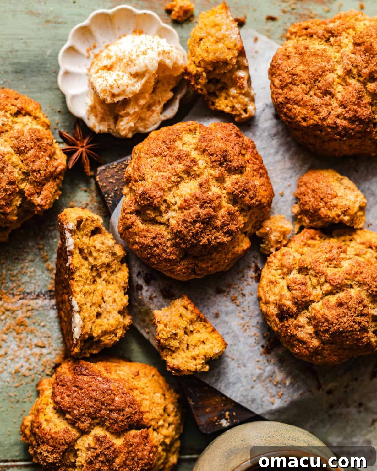 A collection of sweet potato biscuits cooling on a cutting board with parchment paper, showcasing their golden-brown crusts.