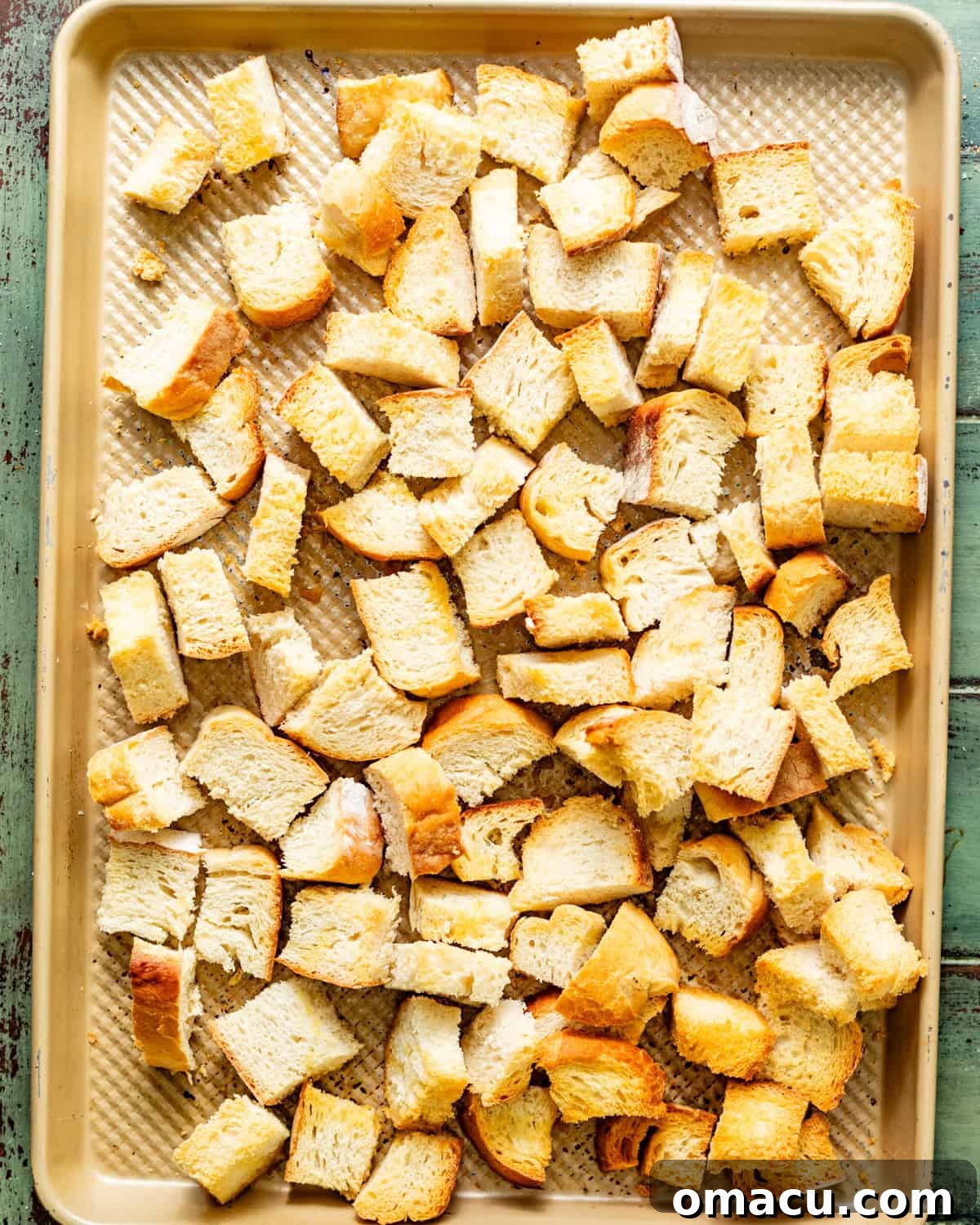 Golden brown toasted sourdough bread cubes on a baking sheet, ready for stuffing.