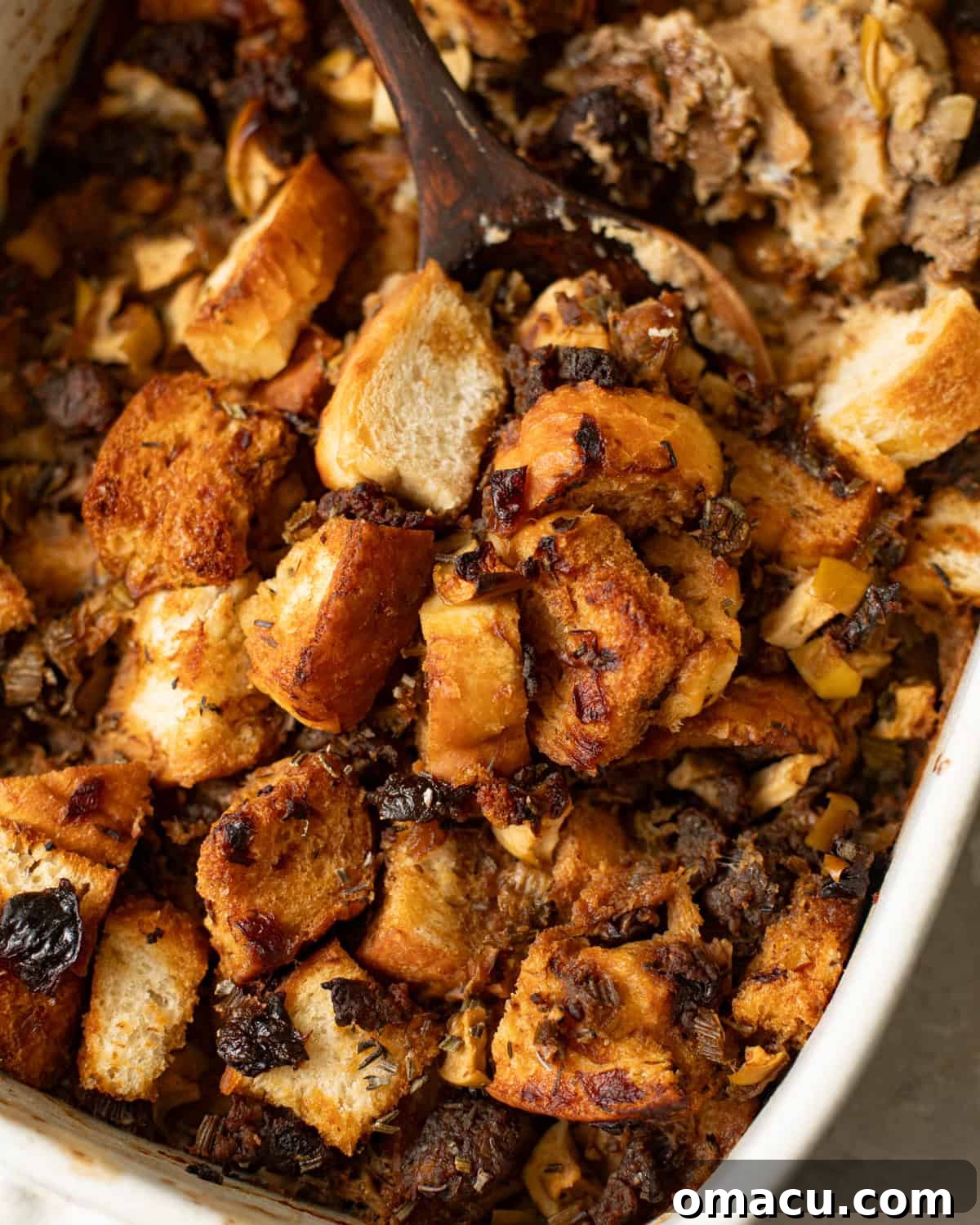 Baked sage and sausage stuffing, golden brown and bubbling, in a casserole dish.