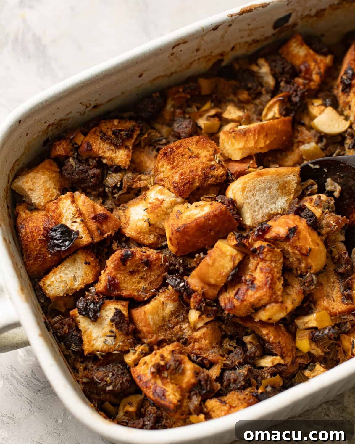 Overhead photo of sage and sausage stuffing, golden and warm, in a large casserole dish, ready to be served.