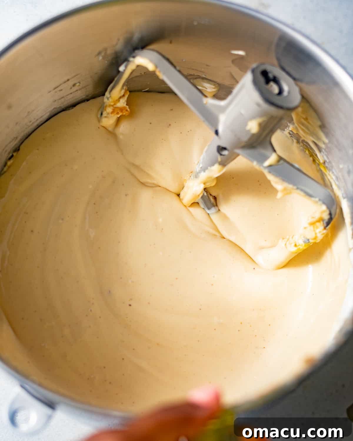 Smooth and creamy pecan cheesecake batter in the bowl of a stand mixer with a paddle attachment, ready for layering.