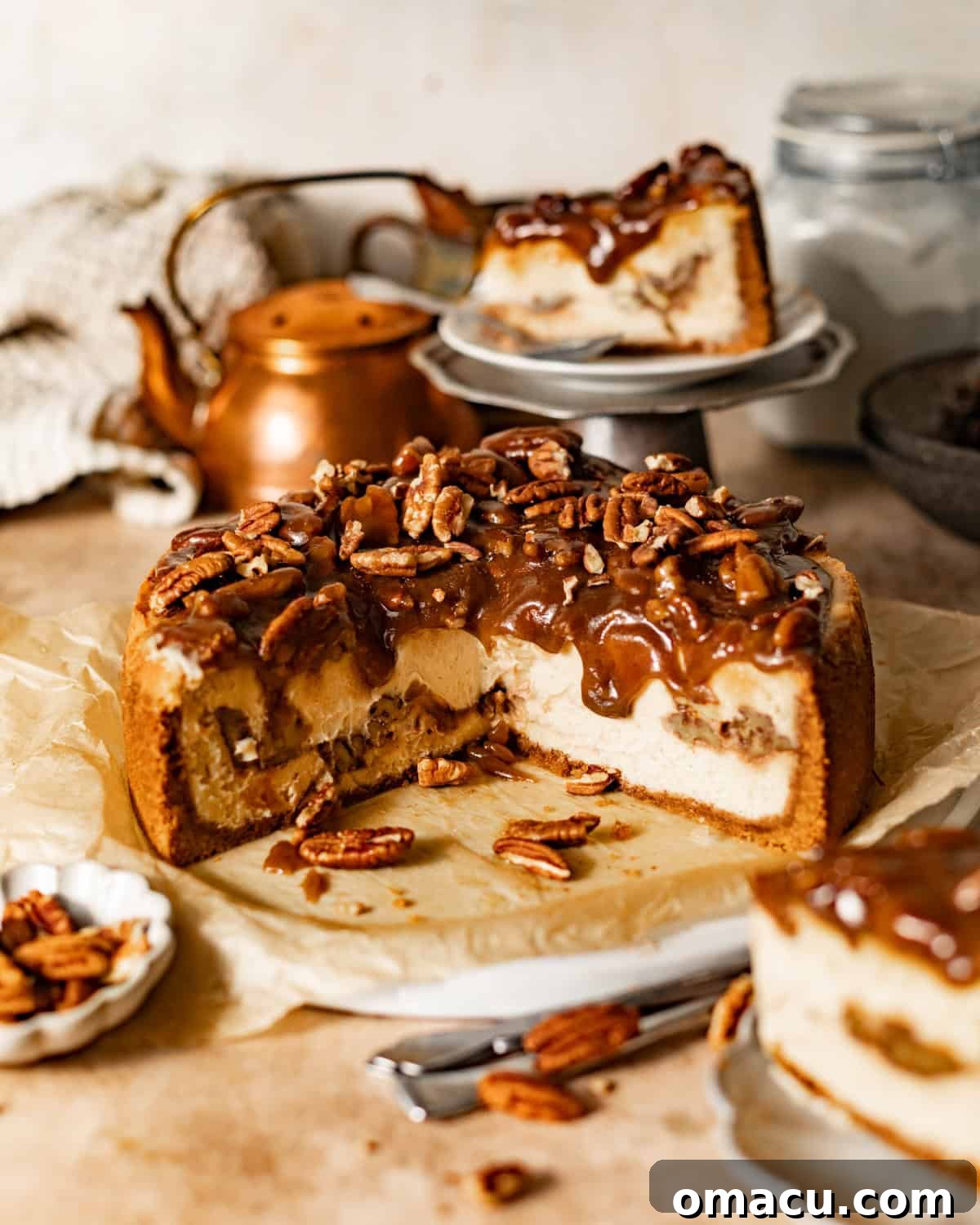 Pecan Pie Cheesecake cut in half on a serving plate, clearly showing the luscious pecan pie layer in the middle of the creamy cheesecake.