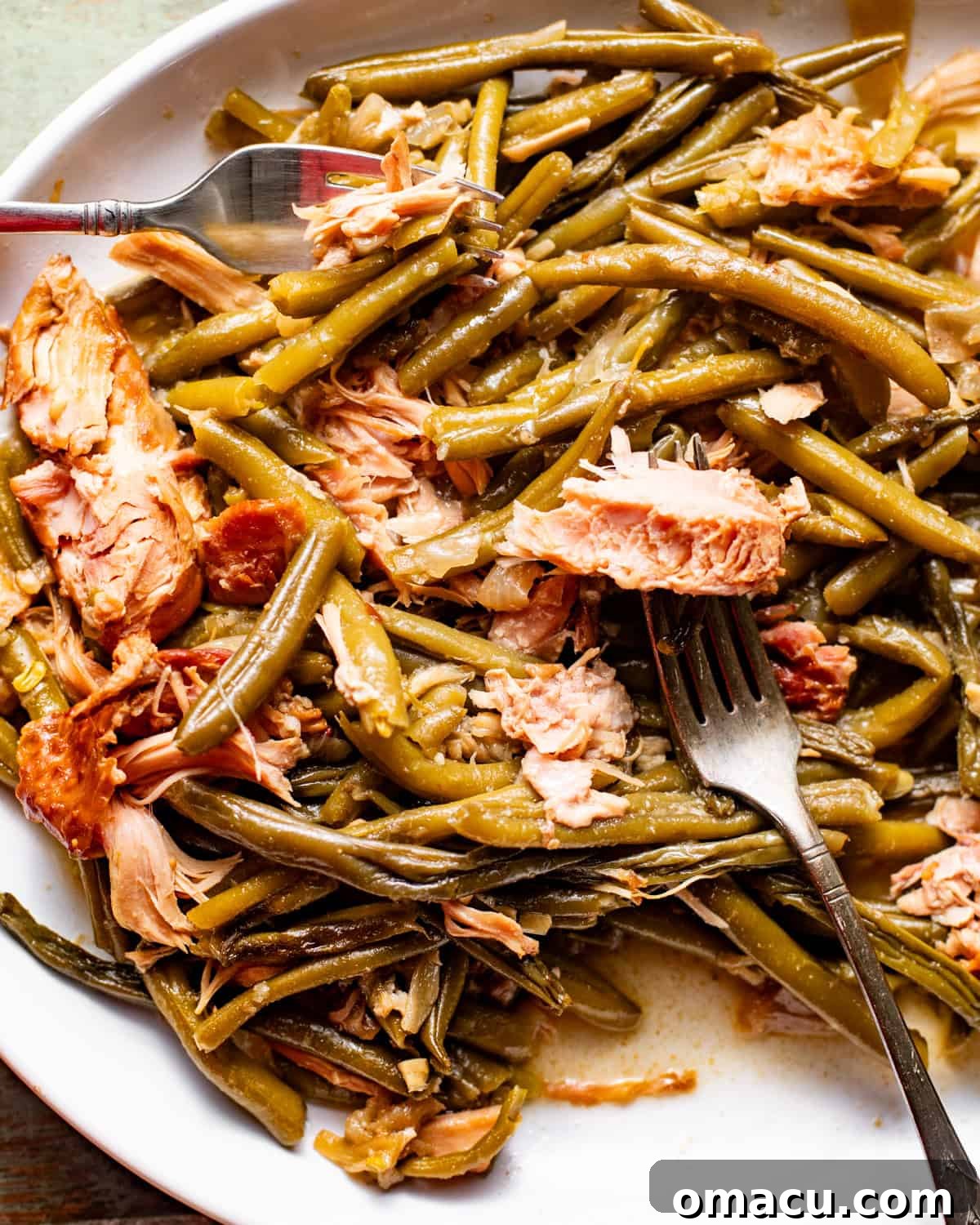 slow cooker green beans with smoked turkey on a serving plate with a serving fork.