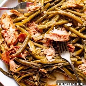 slow cooker green beans with smoked turkey on a serving plate with a serving fork.