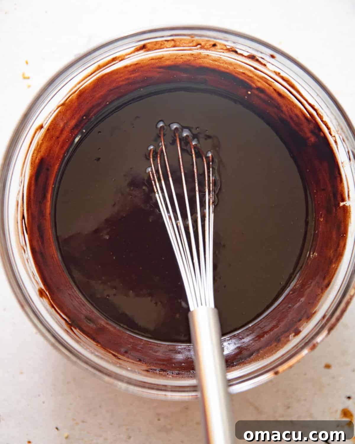 Melted chocolate, butter, oil, espresso powder, and cocoa powder blended smoothly in a bowl for the brownie base.