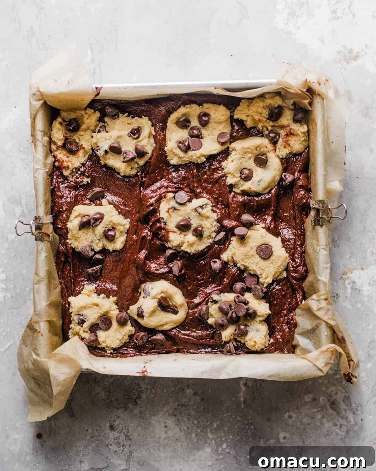 Brookies assembled in a baking pan with cookie dough balls on top, ready for the oven.