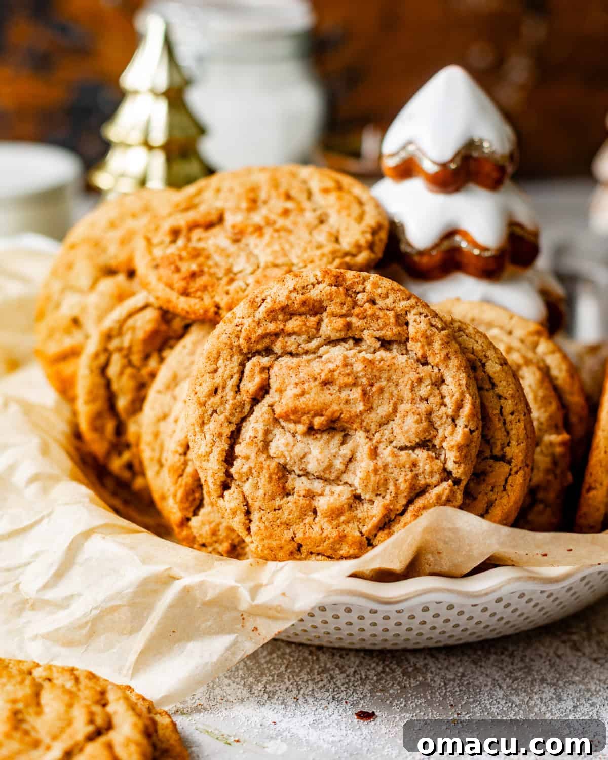 A bowl overflowing with freshly baked brown butter snickerdoodle cookies, lined with parchment paper.