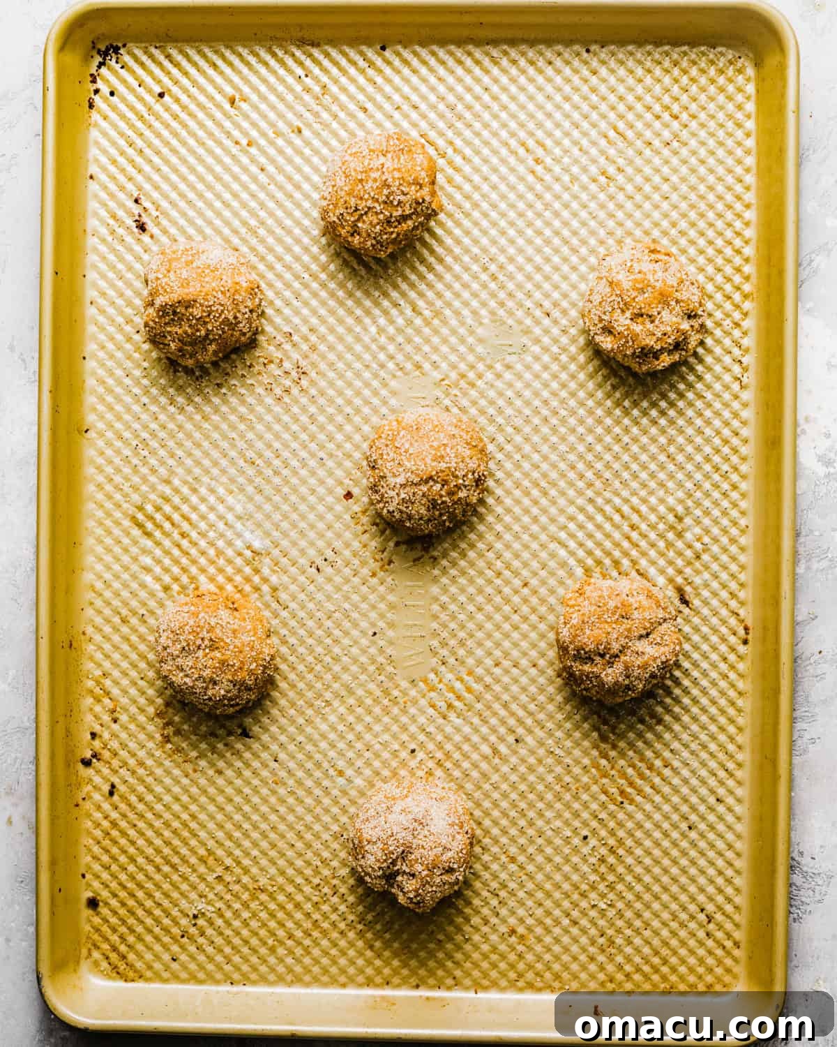 Scooped cookie dough balls placed on a parchment-lined baking sheet, ready for chilling.