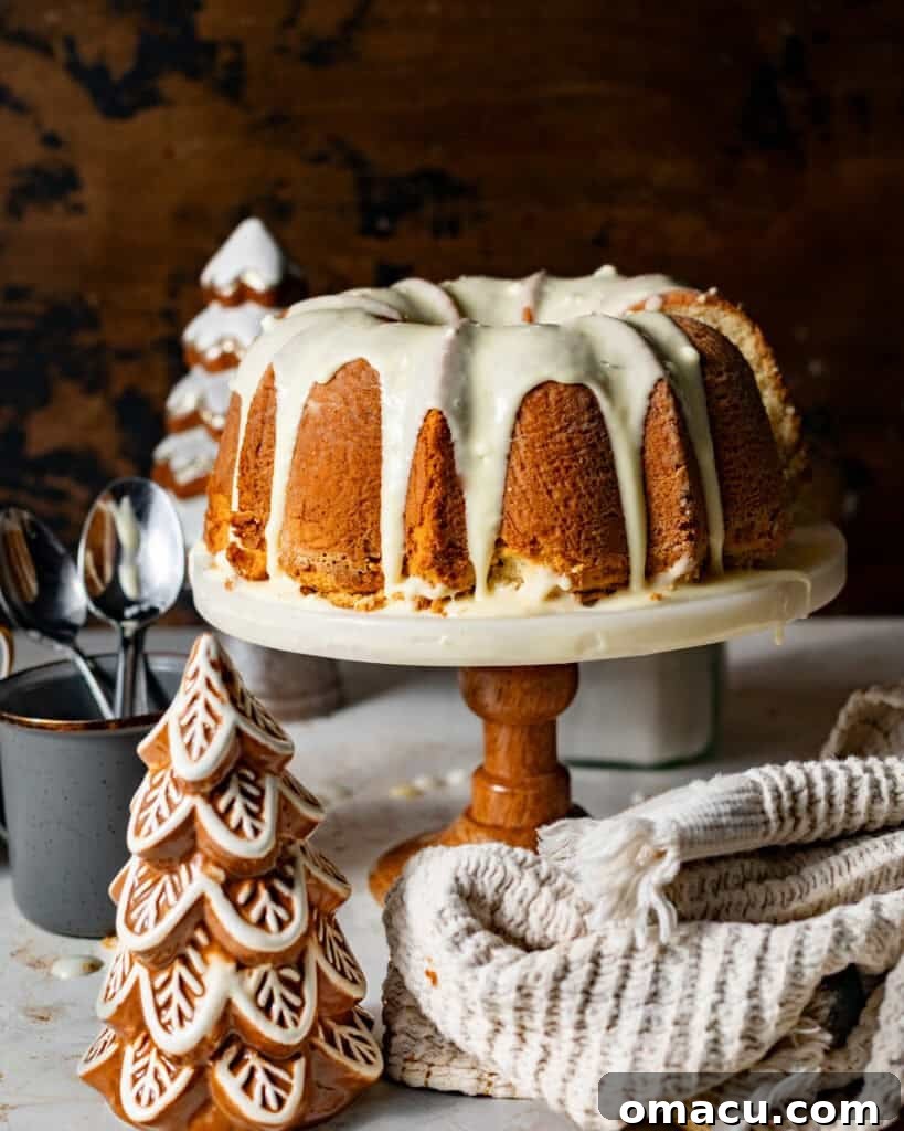 A perfectly baked Eggnog Pound Cake resting elegantly on a cake stand, generously covered in a shimmering spiced eggnog glaze and lightly dusted with freshly grated nutmeg, ready to be the centerpiece of holiday celebrations.