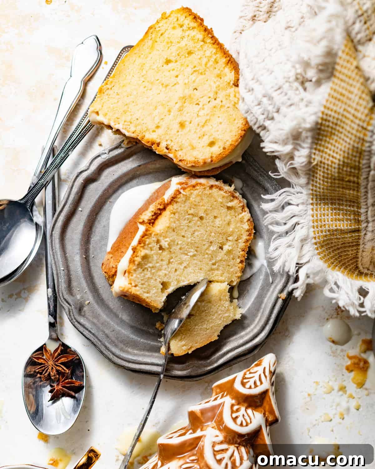 Beautifully sliced eggnog pound cake pieces are artfully arranged on individual dessert plates, gracefully showcasing its moist, rich interior and radiating an inviting, warm holiday aroma.