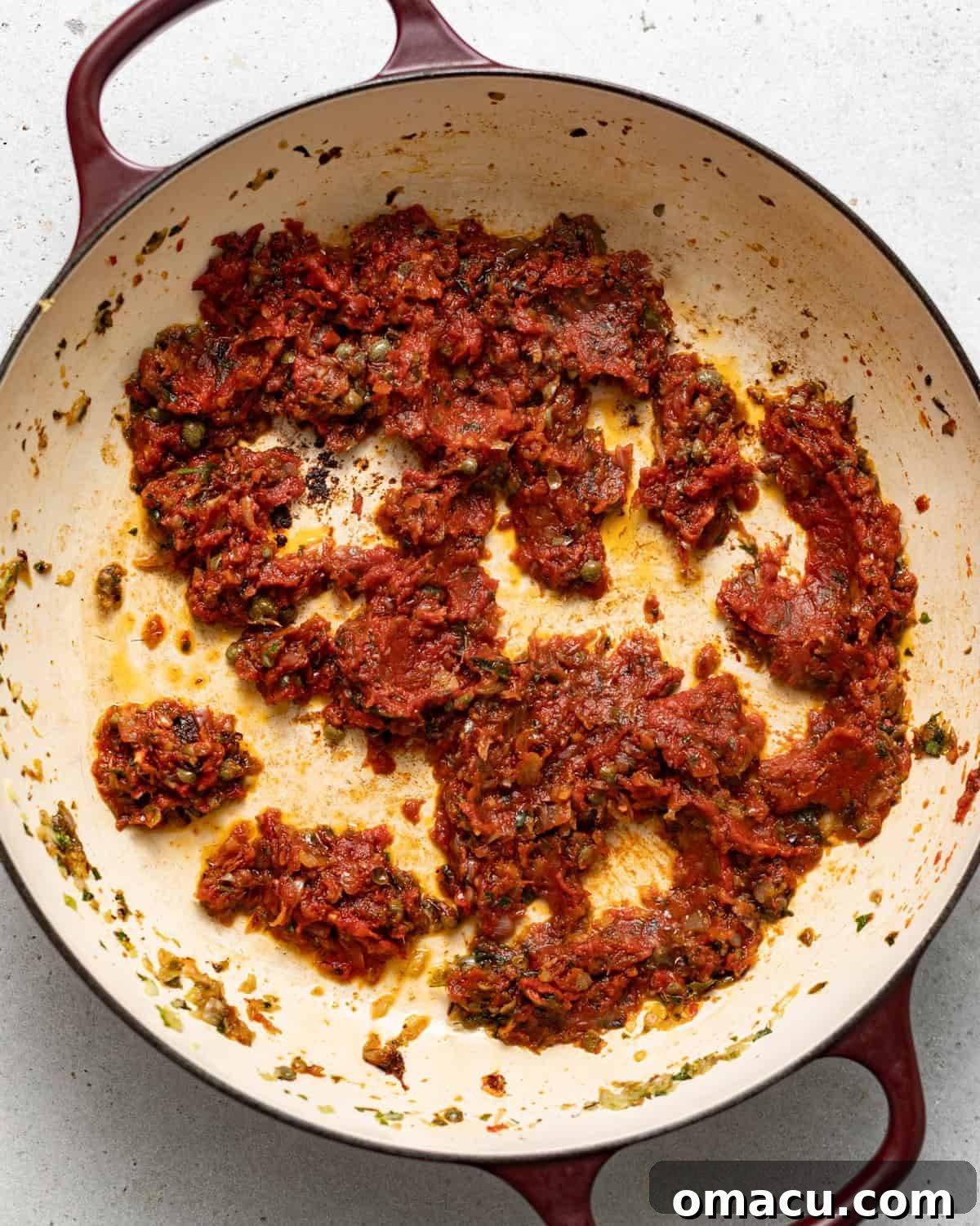 Shallots, minced garlic, a mix of seasonings, and rich tomato paste cooking together in a skillet, creating an aromatic base.