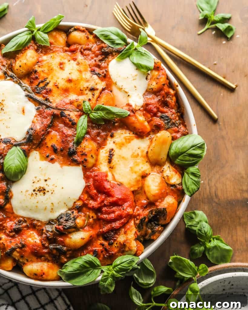A close-up of Sausage and Spinach Gnocchi Bake, showcasing the melted mozzarella and rich sauce