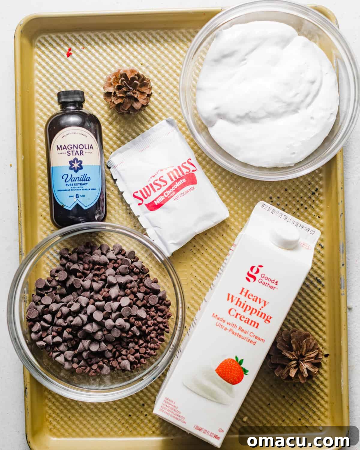A perfectly arranged selection of ingredients: heavy cream, semi-sweet chocolate chips, fragrant vanilla extract, a packet of hot cocoa mix, and soft marshmallow fluff, all prepared for crafting the decadent dip.