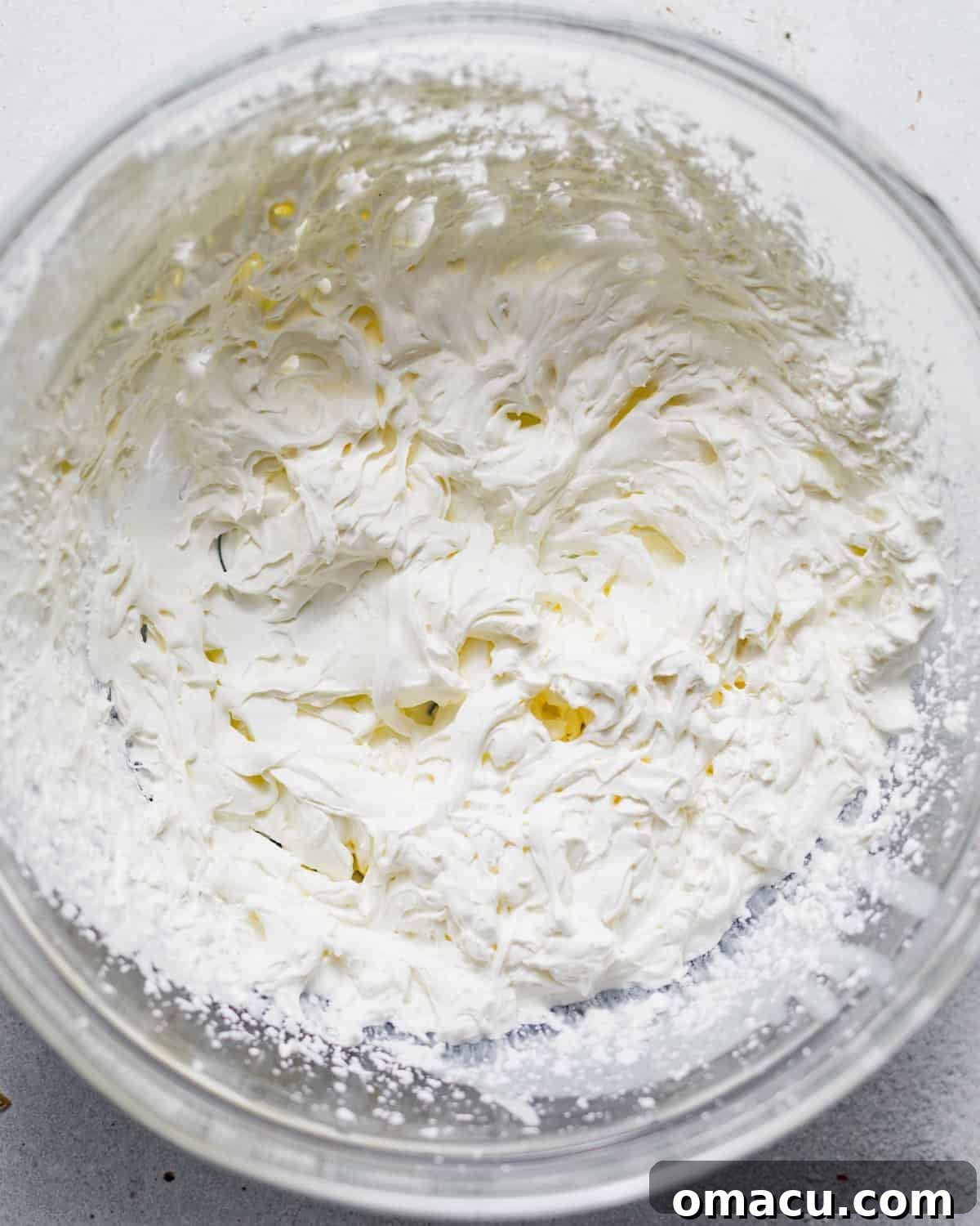 Remaining heavy cream, marshmallow fluff, and vanilla extract being vigorously beaten together in a large mixing bowl using an electric hand mixer, creating a light, airy, and stiff-peaked whipped cream mixture.