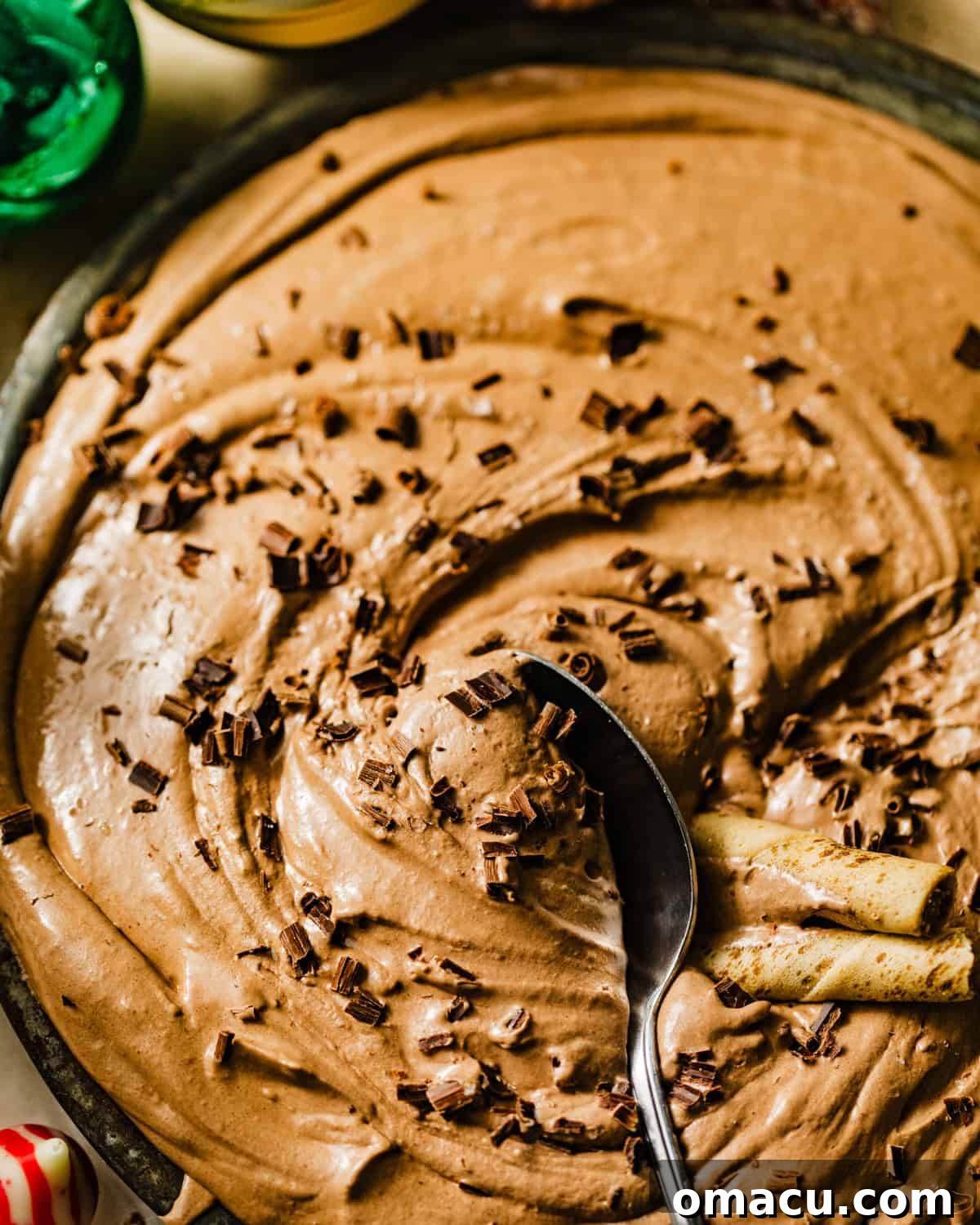 A spoon scooping a generous portion of the finished hot chocolate dip, beautifully topped with delicate chocolate shavings, inviting a taste and showcasing its creamy texture.