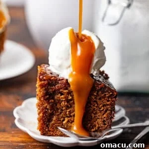 A slice of sticky toffee pudding on a small plate with a spoon. There's ice cream on top of the cake with toffee sauce being poured on top.