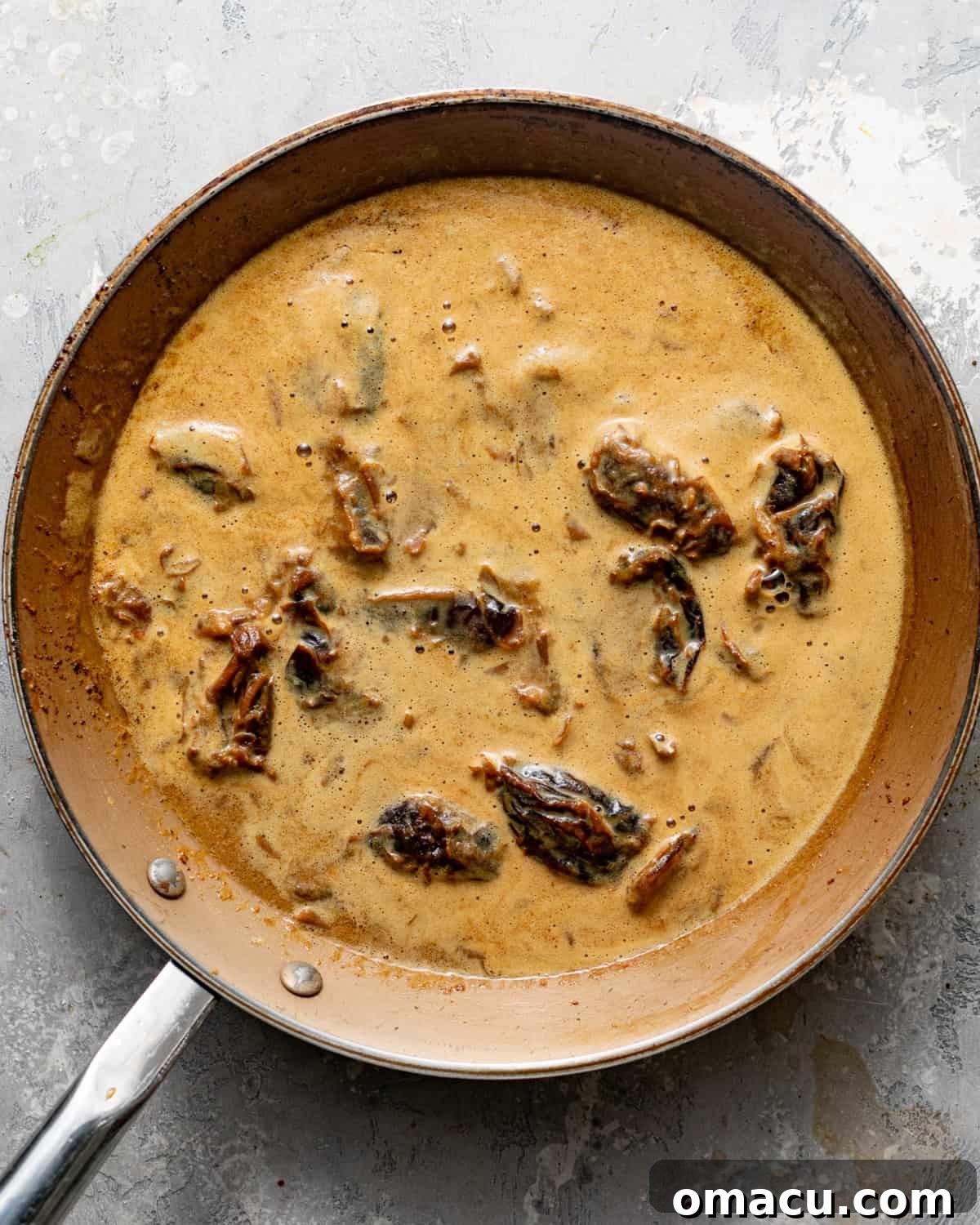 Dates in a pan soaking in warm milk, molasses, and baking soda.