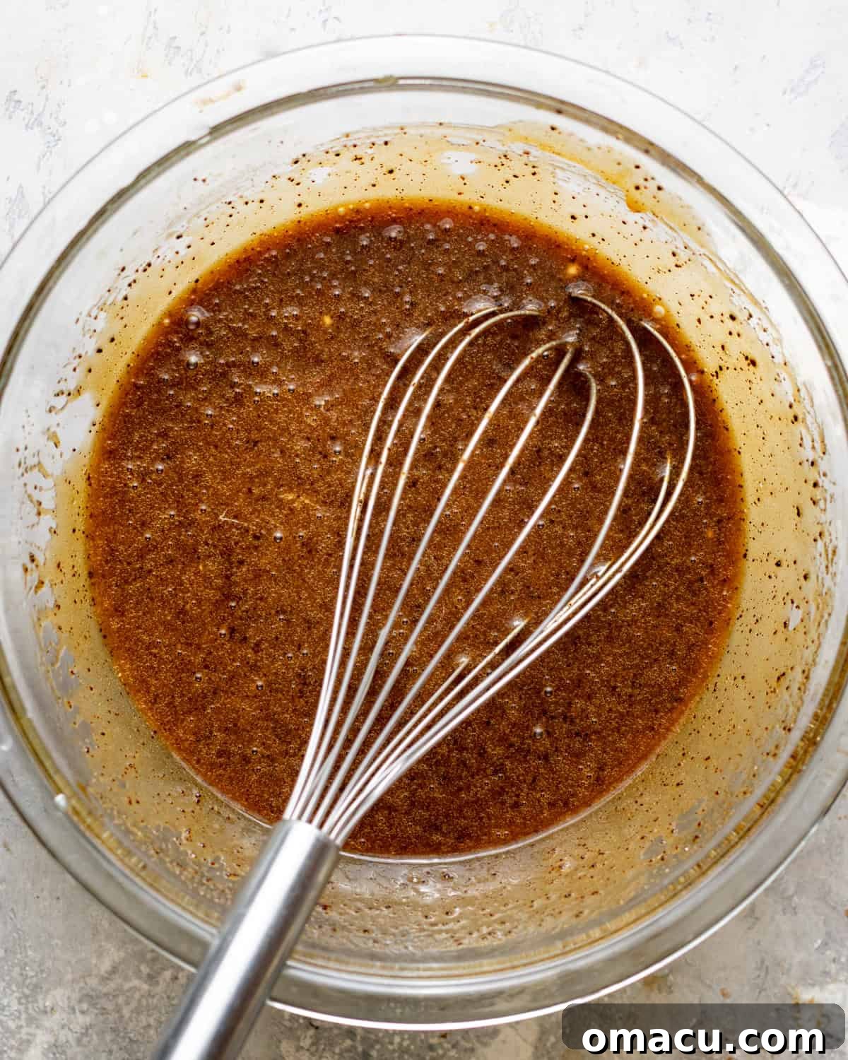Browned butter, sugar, eggs, oil, and sour cream whisked together in a bowl.