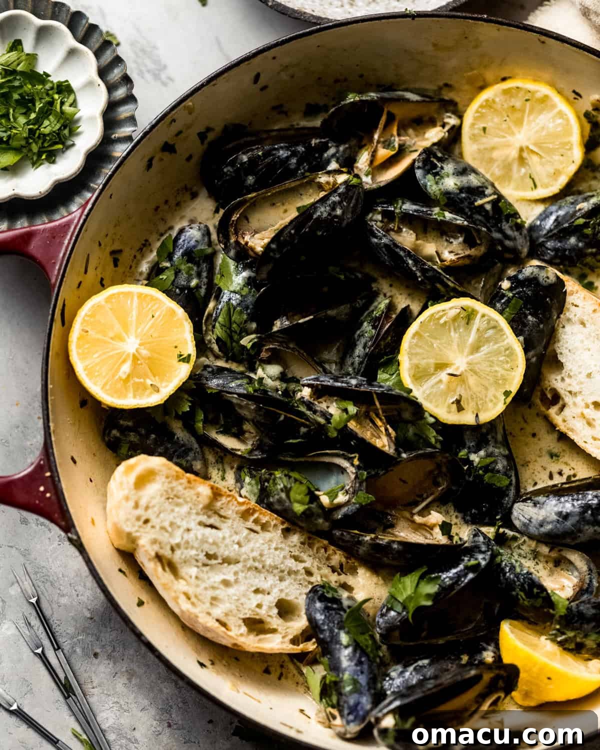 Overhead photo of mussels cooking in a pan covered in white wine sauce.