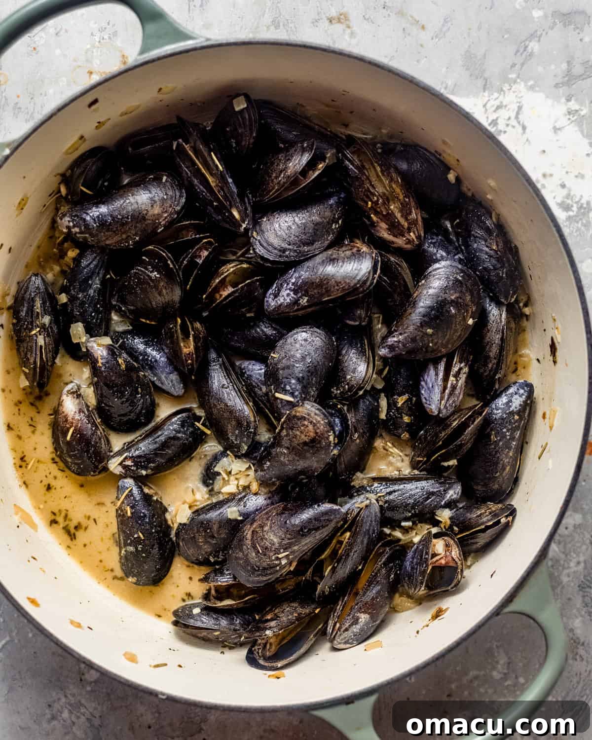 Mussels cooking in a pan, steaming gently in the white wine sauce.