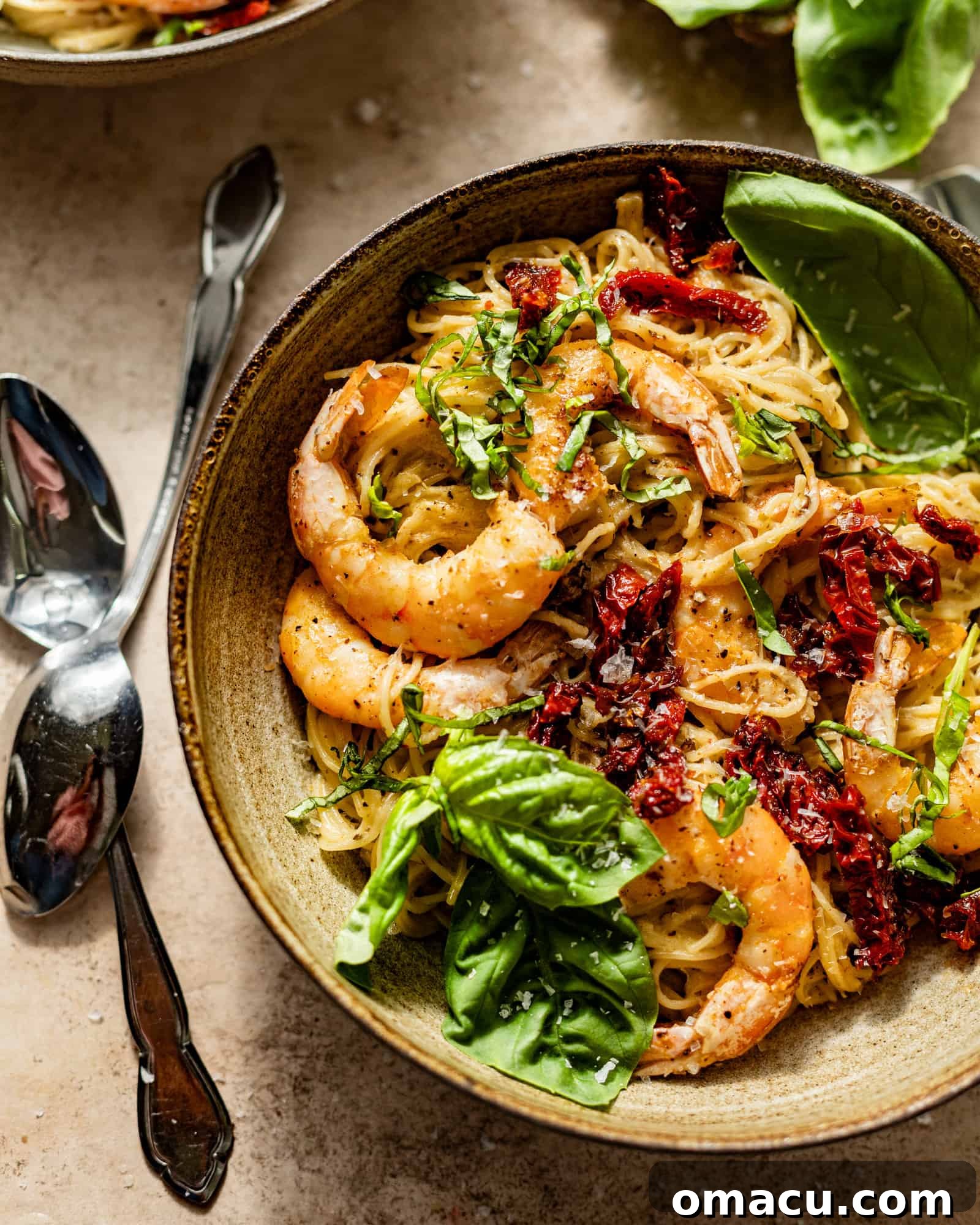 A beautifully plated bowl of Creamy Pesto Shrimp Pasta, garnished with fresh basil and sun-dried tomatoes.