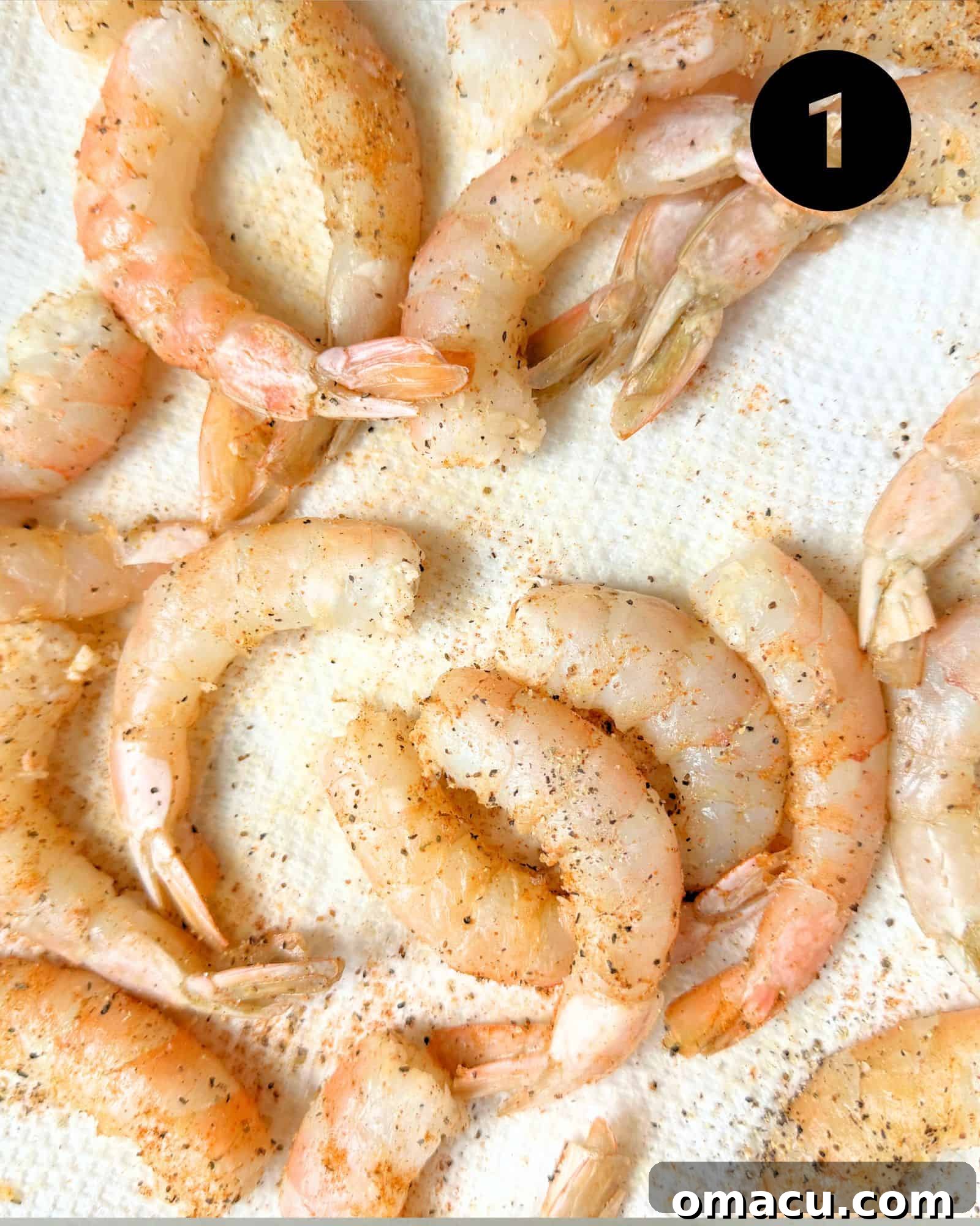 Raw, seasoned shrimp resting on a paper towel, ready for cooking.