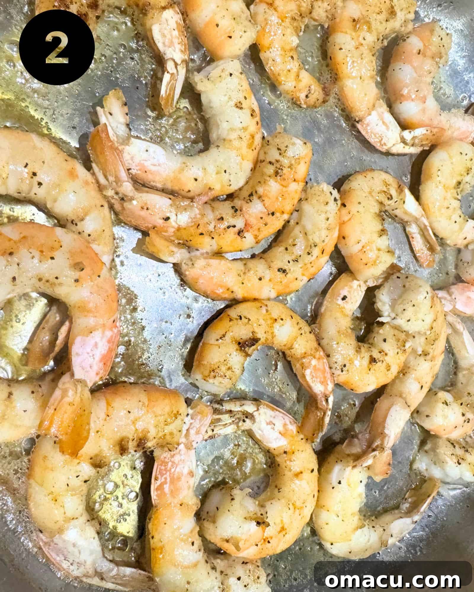 Shrimp cooking in a sauté pan, beginning to turn pink and curl.