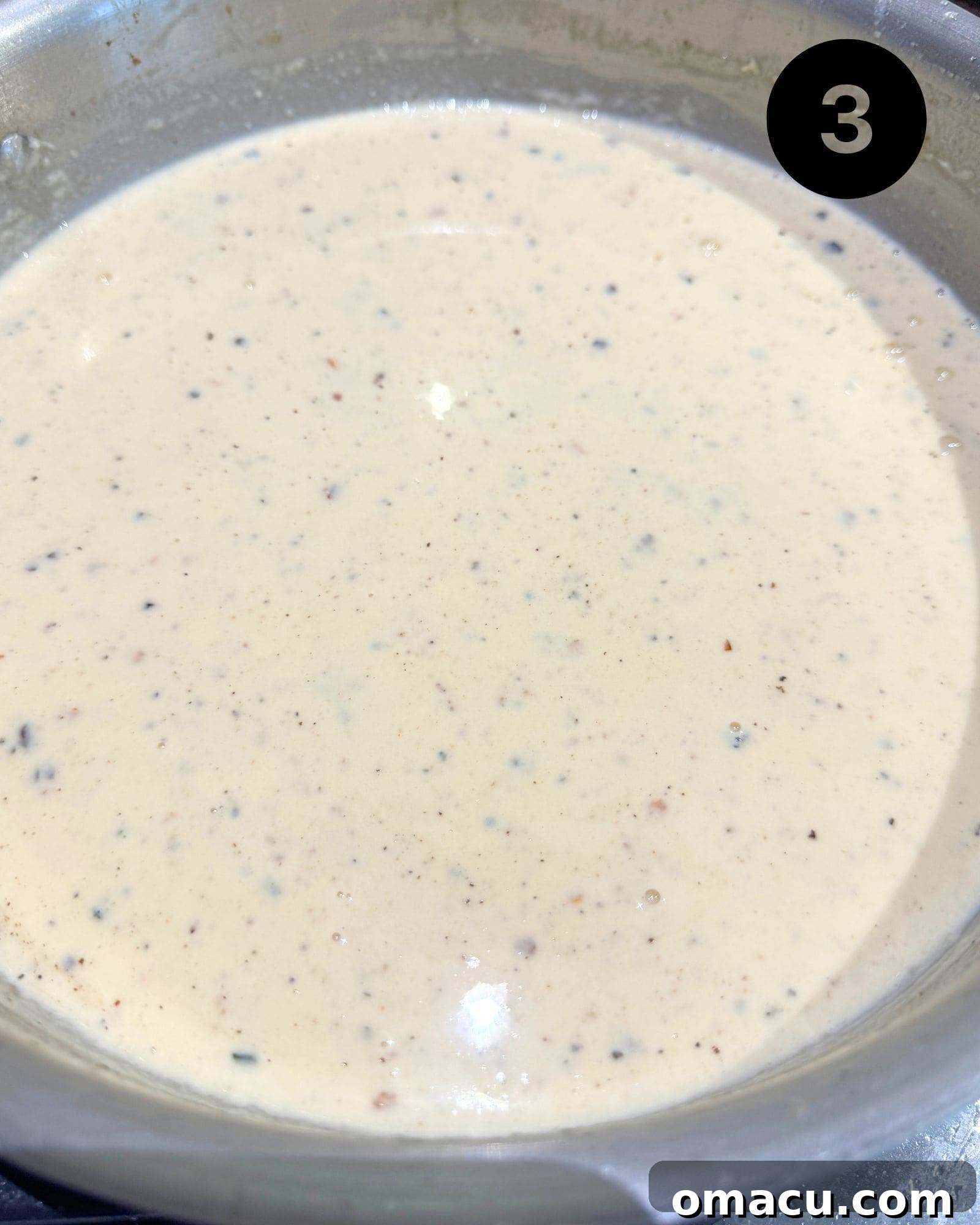 The white wine cream sauce simmering in a large saucepan, creating a rich base for the pesto.