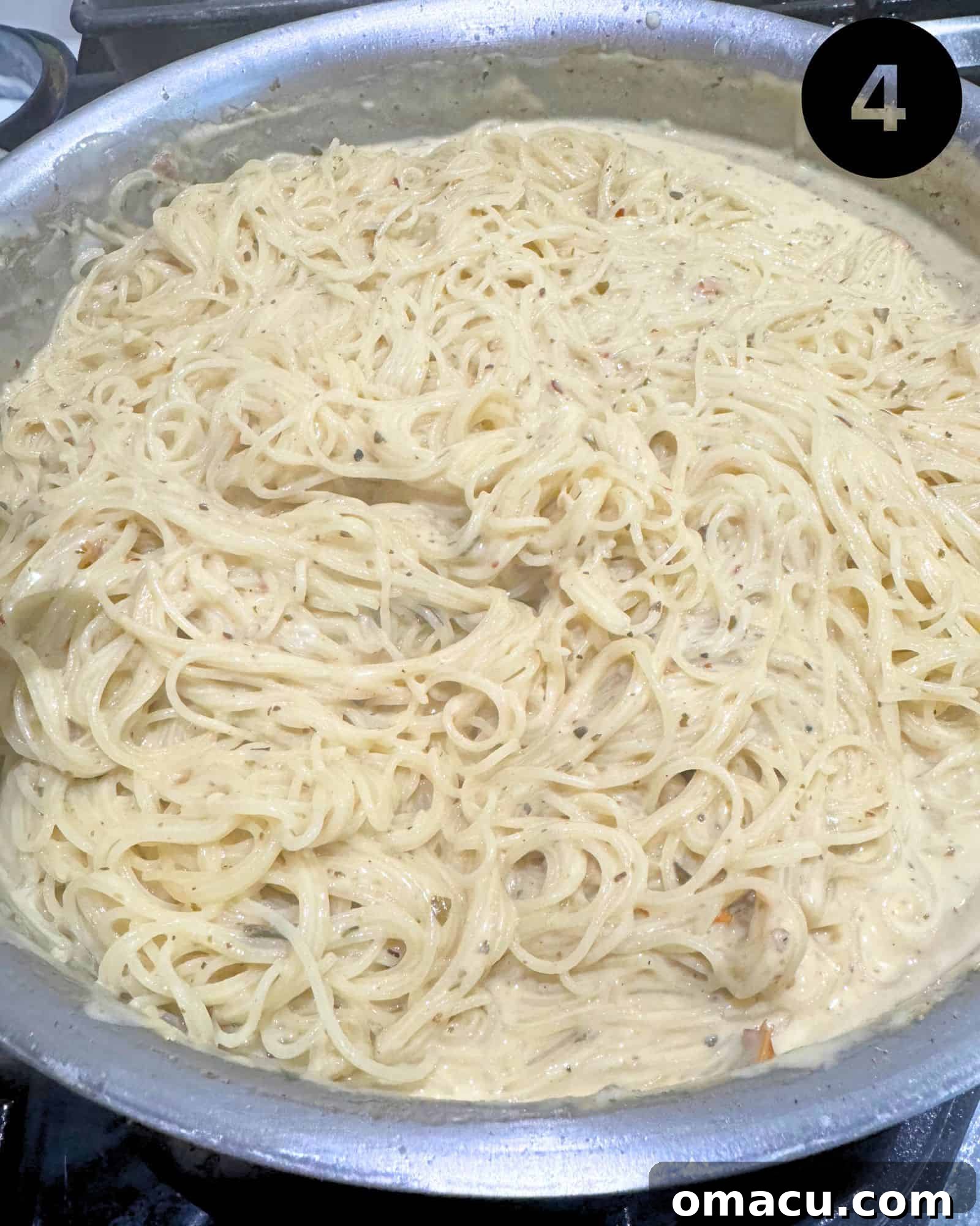 Angel hair pasta being tossed with the rich, creamy white wine sauce before adding shrimp.