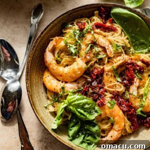 pesto pasta with shrimp in a large bowl with forks and spoons