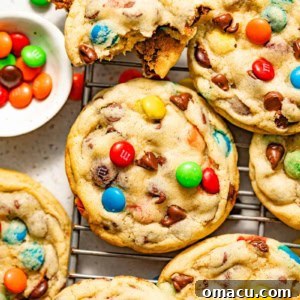 M&M chocolate chip cookies on a wire rack with a bowl of candies.