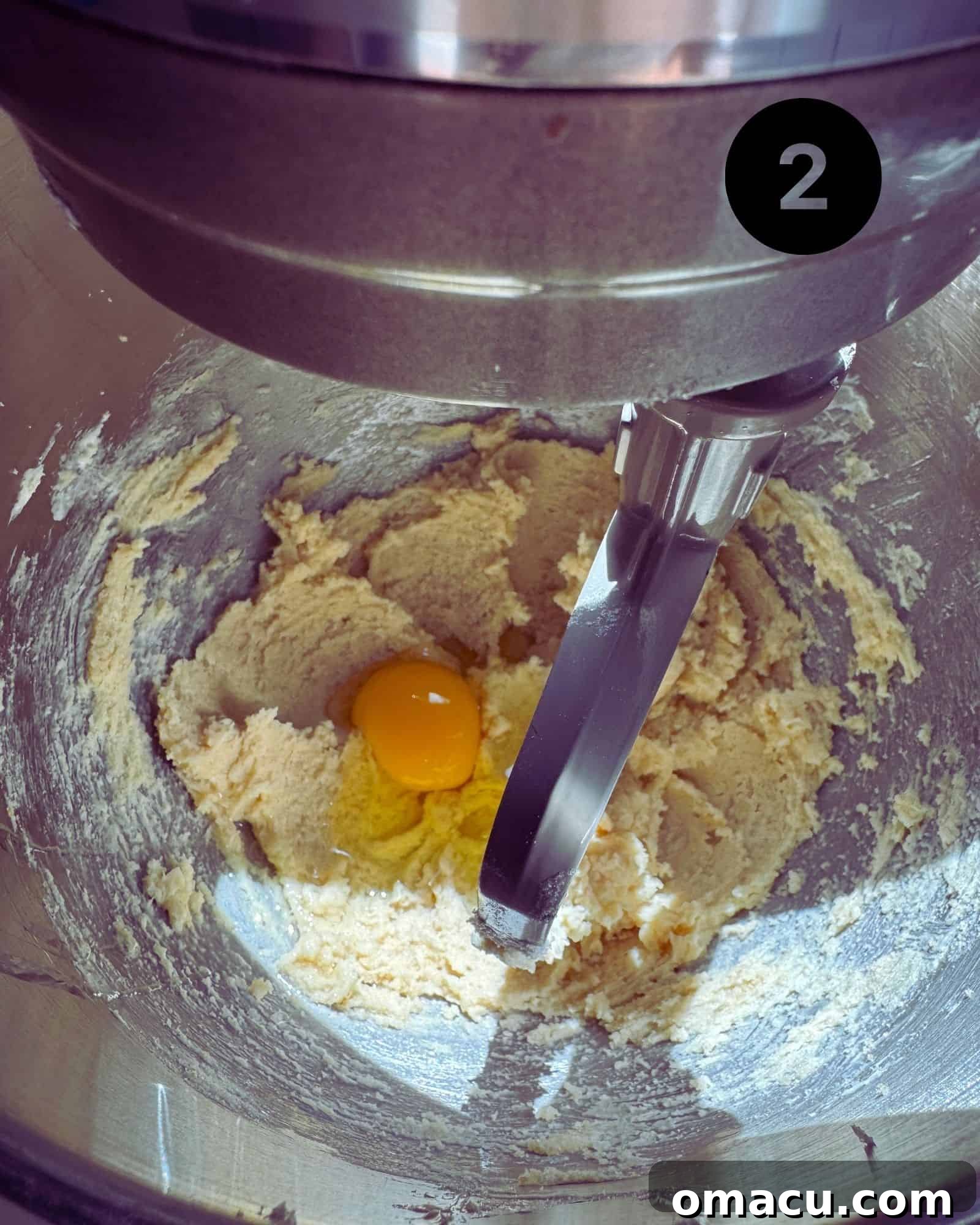 Butter, sugar, and an egg mixture being creamed together in a stand mixer, showing the incorporation of wet ingredients.