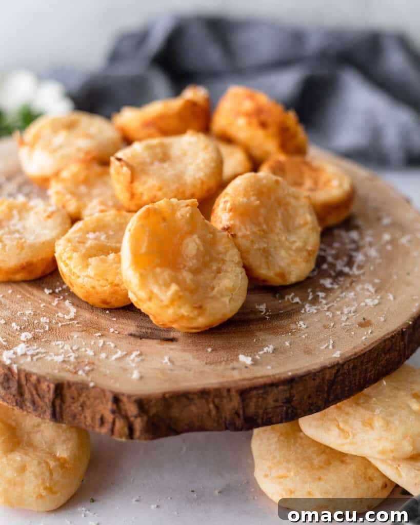 Pao De Queijo on a wooden cheese board with fresh herbs in the background