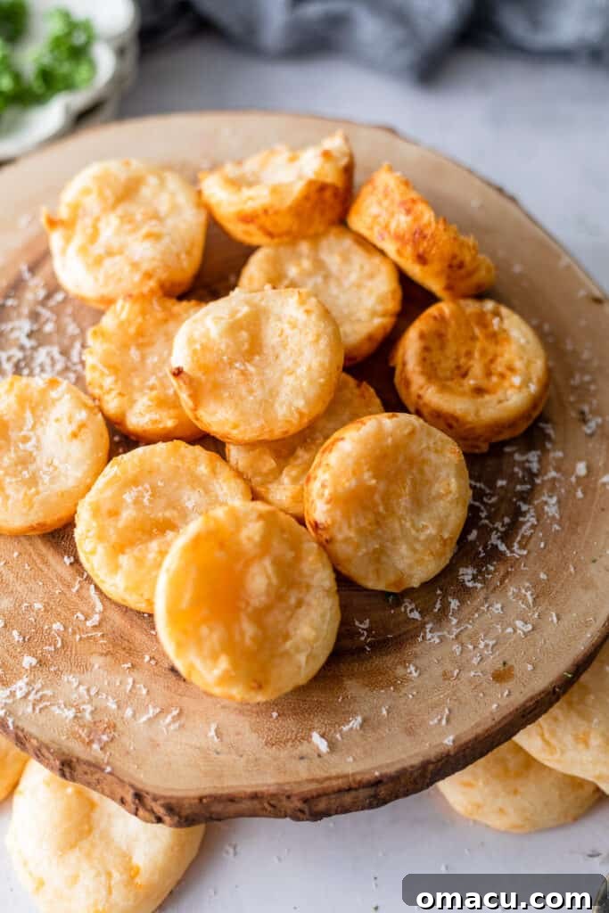 Pao De Queijo on a wooden cheese board with fresh herbs in the background