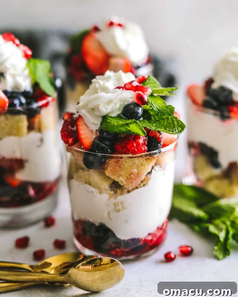 Individual Mixed Berry Trifles in clear glass cups, garnished with fresh berries and spoons, ready to be enjoyed.