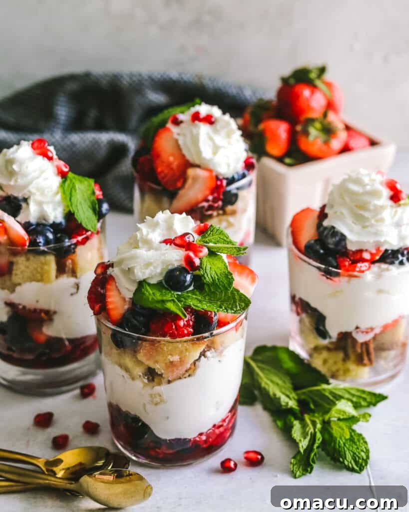 A row of five individual Mixed Berry Trifles in clear cups, neatly arranged and ready for serving.