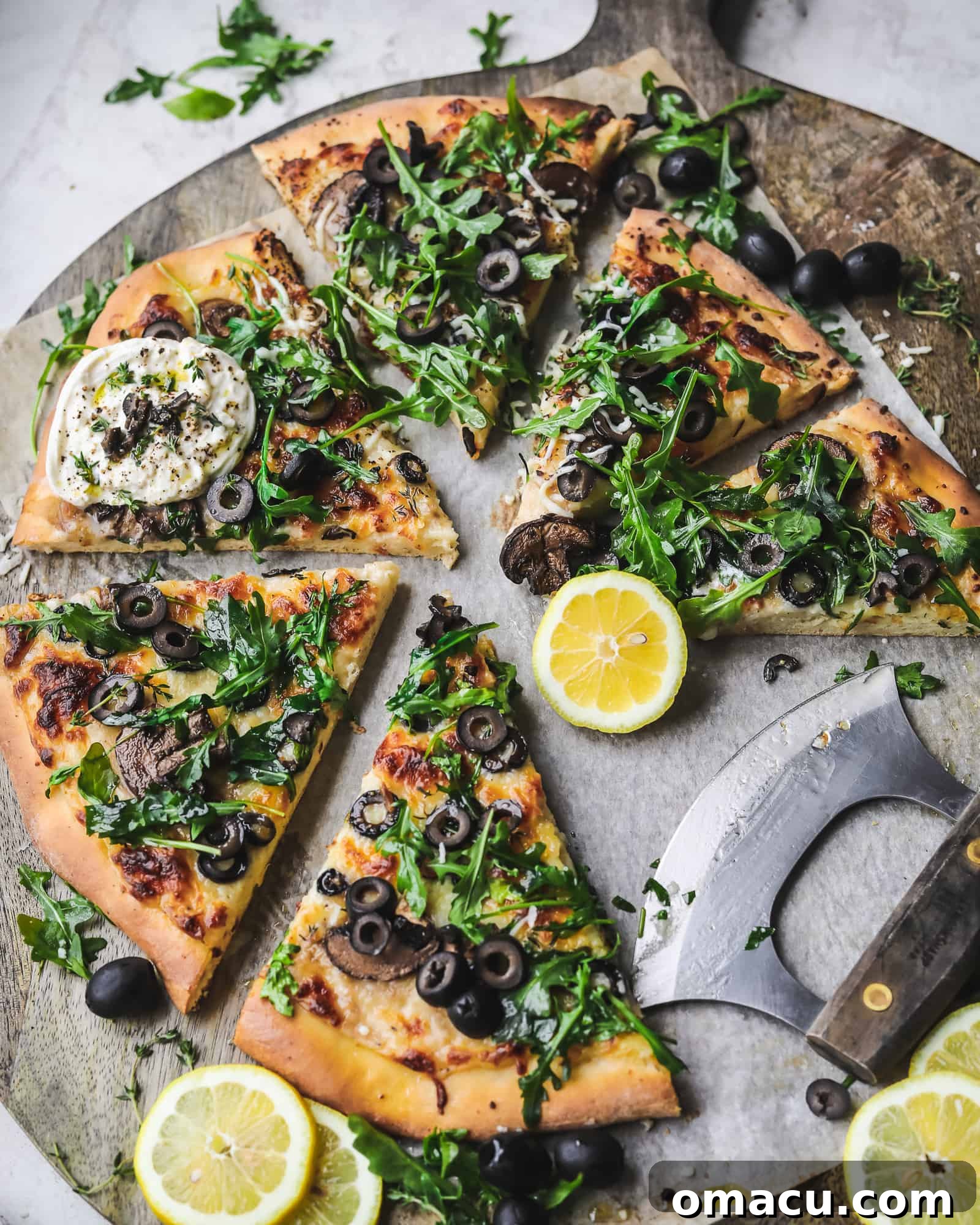Delicious Black Olive Pizza adorned with fresh arugula and creamy burrata on a rustic cutting board
