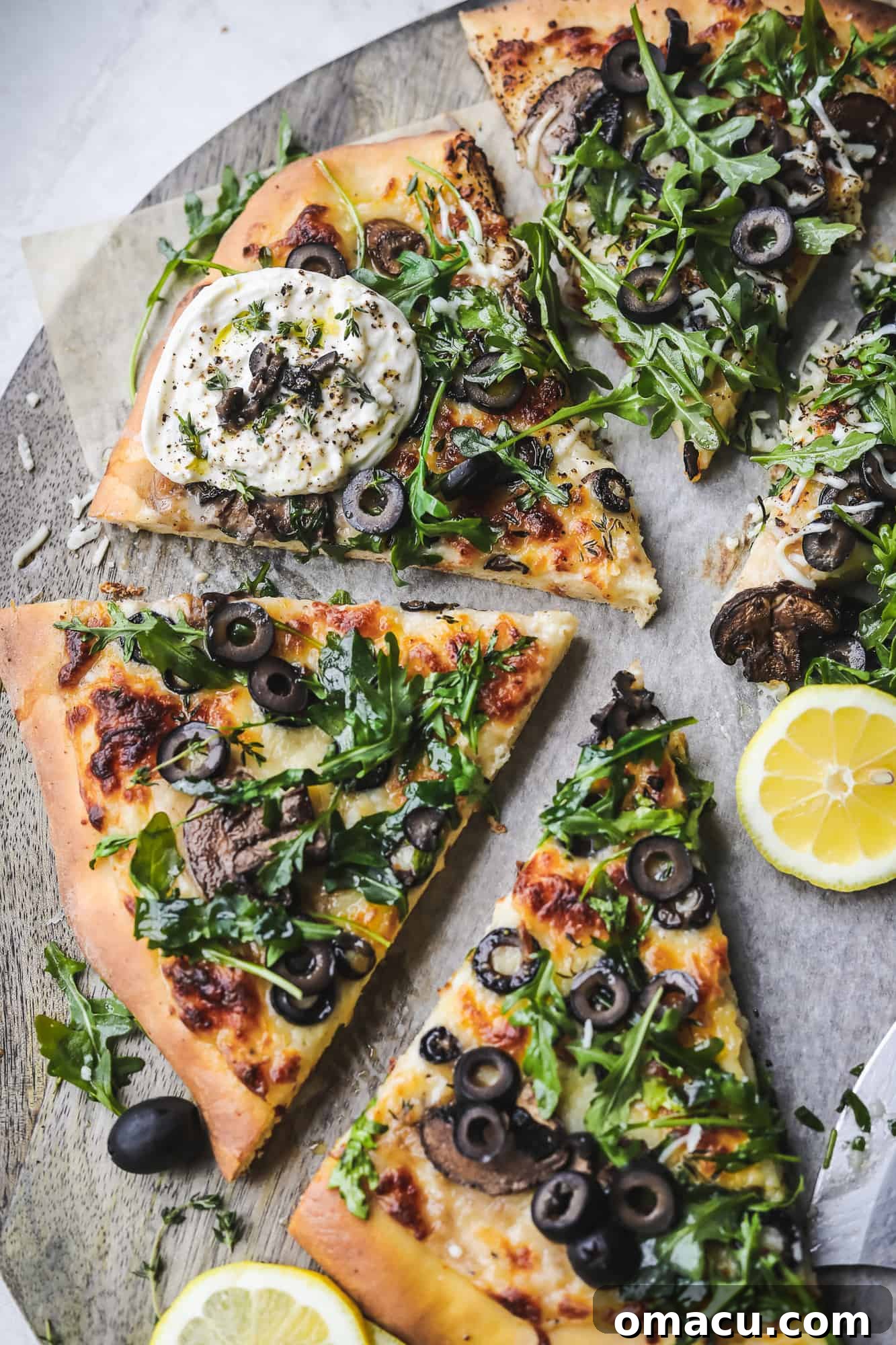 A large slice of Black Olive Pizza being taken from the cutting board