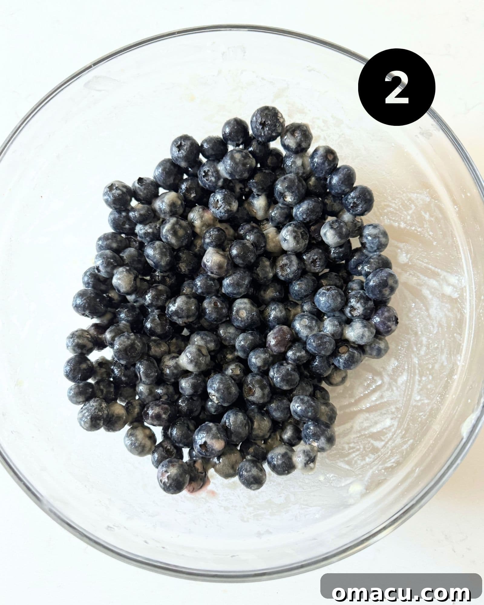 Fresh blueberries coated with lemon juice, flour, and sugar in a bowl, ready to be added to the cake.