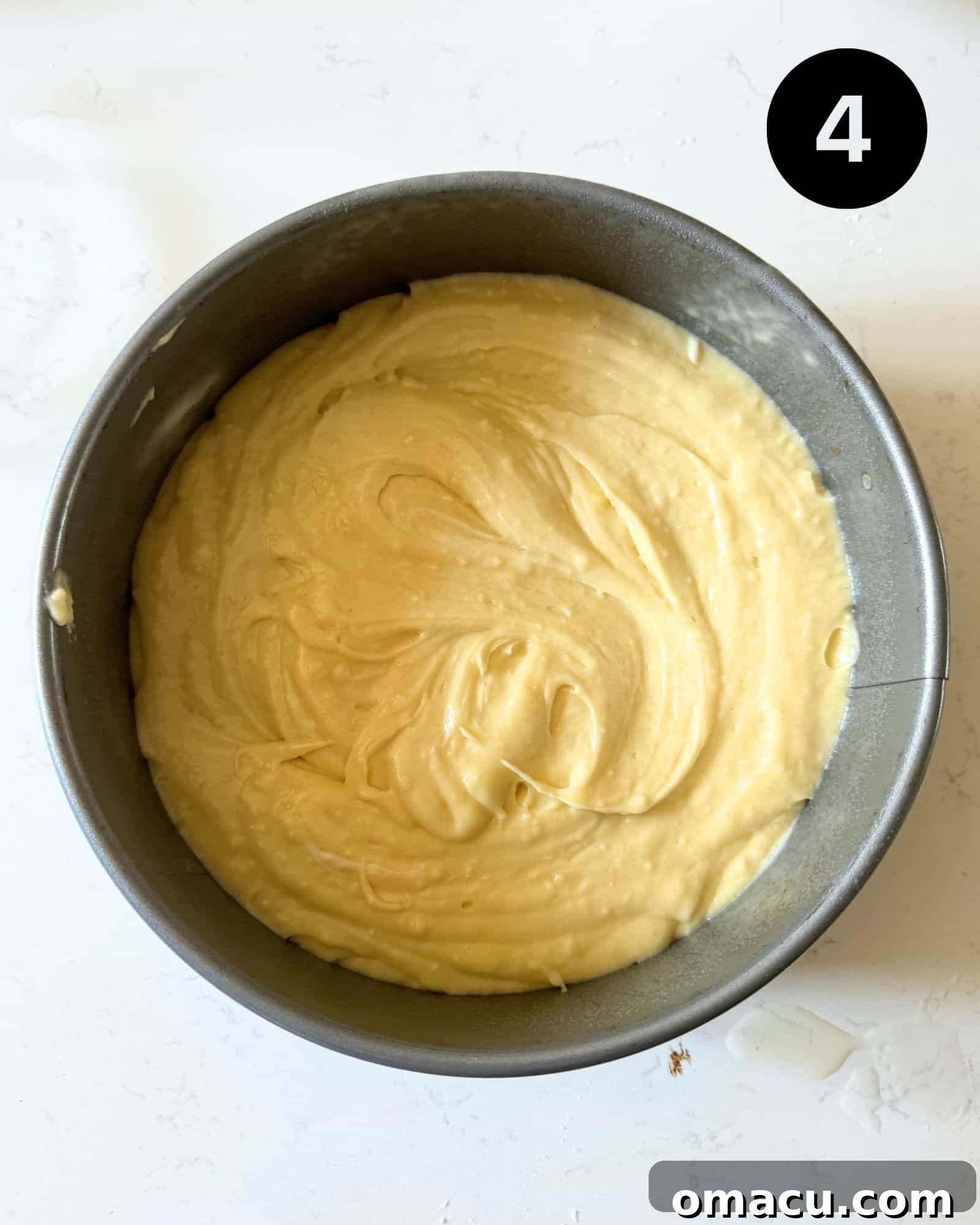 Smooth coffee cake batter evenly spread in a greased springform pan, ready for the next layer.