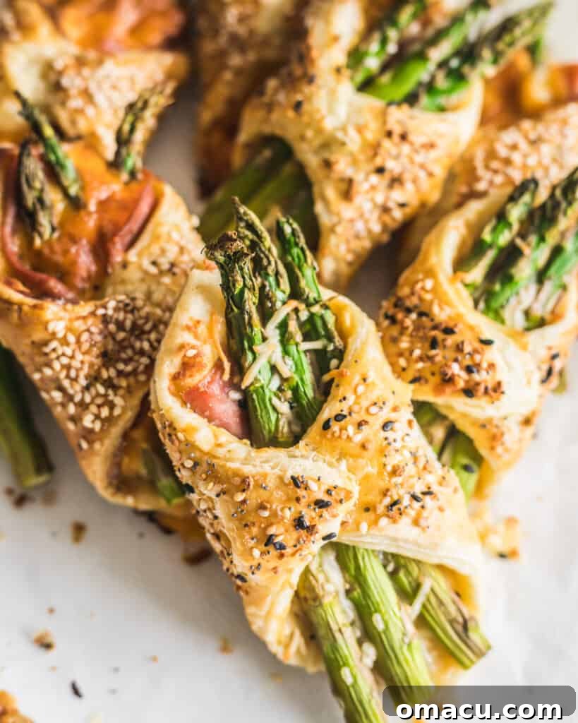 Asparagus and Prosciutto Puff Pastry Bundles on a piece of parchment paper, fresh out of the oven