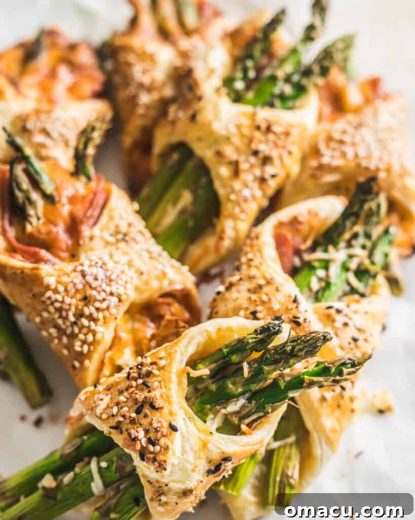 A close-up of a single Asparagus and Prosciutto Puff Pastry Bundle, showcasing its golden layers