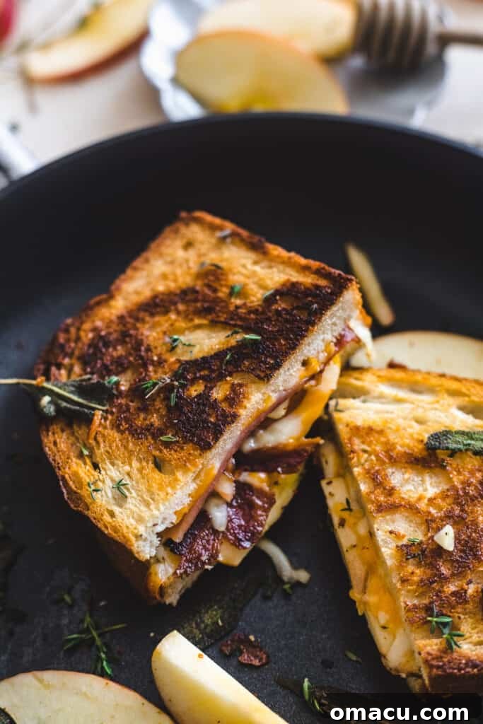 A close-up of the delicious Apple Bacon Cheddar Grilled Cheese on a cutting board, ready to be enjoyed.